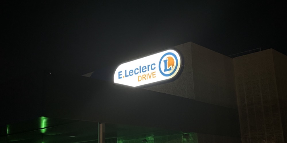 Caisson lumineux E.Leclerc Drive allumé au sommet de son mât, la nuit