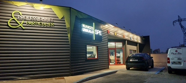 Logos et bandeau lumineux de Nuances Unikalo et SPE sur la façade du magasin, la nuit, Dole