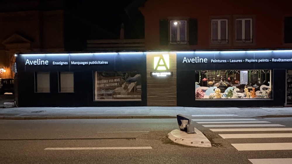 La façade du magasin Aveline la nuit, enseignes allumées, Bitschwiller-lès-Thann