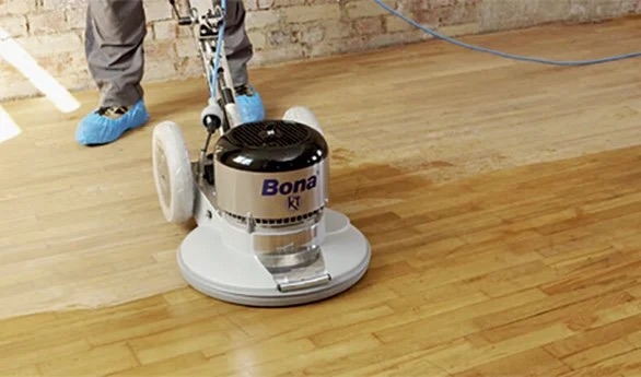 Une ponceuse à parquet en train de poncer un plancher en bois